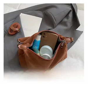 Detail showing the internal storage capacity of the brown suede satchel bag with essentials