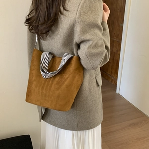 Brown faux suede bucket bag with geometric wide strap shown on a model's shoulder
