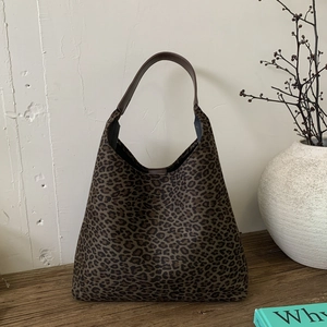 Detail van retro luipaard hobo tas met bruine lederen riem in een huiselijke sfeer
