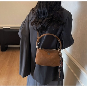Close-up of brown suede tote bag with leopard print charm and metallic top handles