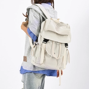 Vista laterale dello zaino in nylon beige indossato, mostra capacità e tasche laterali