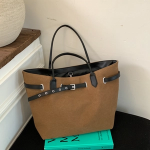 Detail einer braunen Canvas-Tasche mit schwarzen Ledergriffen und Metallösen