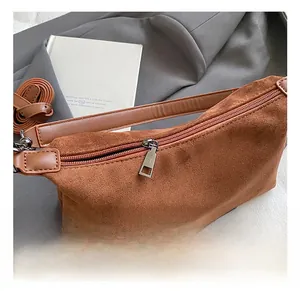 Detail of caramel suede pillow bag with metal zipper on a dark blazer background