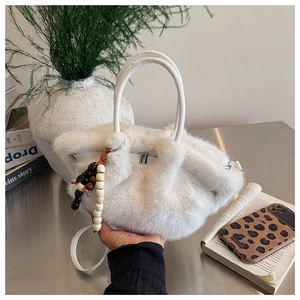 Nahaufnahme der weißen Kunstpelz-Handtasche mit Holzperlen-Anhänger und Gurt