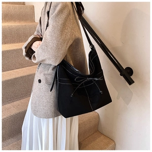 Detail view of black hobo bag with contrast stitching and bow decoration on shoulder