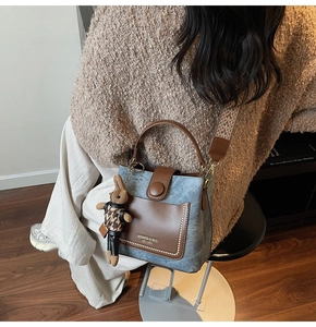 Detail of denim and leather bucket bag with woven strap and a cute rabbit charm