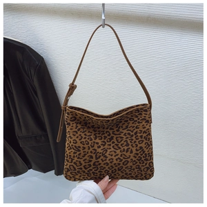 Dettaglio della borsa a spalla leopardata con tracolla in pelle marrone su muro bianco