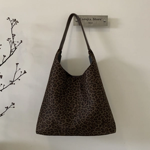 Detail van de grote luipaardprint tote bag met leren riemen hangend aan een witte muur