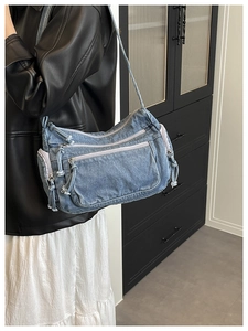 Detail view of light blue denim crossbody bag with multi-pocket cargo design and tassels