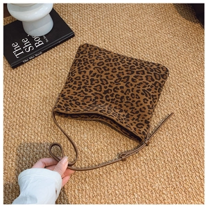 Dettaglio della borsa a secchiello leopardata su tappeto intrecciato con arredamento retrò