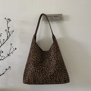 Gedetailleerde weergave van de vintage luipaardprint en bruine riem op een tote bag