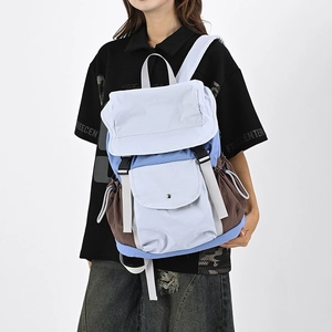 Dettaglio di uno zaino patchwork blu e marrone con chiusura a fibbia e tasche laterali