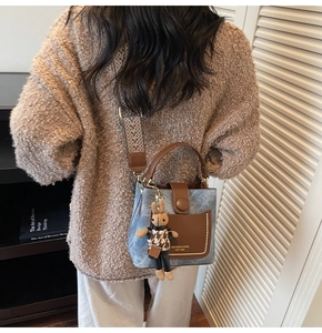 Detail of blue textured bucket bag with brown leather trim and cute rabbit charm