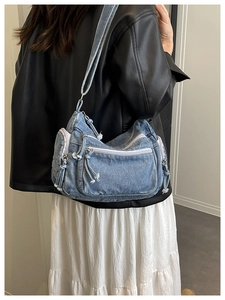 Detail showing multiple zipper pockets and washed denim texture of the crossbody bag