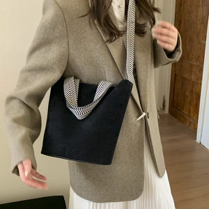 Detail view of black faux suede bucket bag with stylish herringbone patterned strap