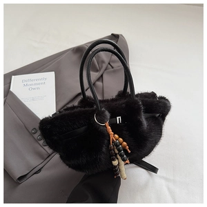 Nahaufnahme der schwarzen Kunstpelltasche mit Ledergriffen und bunter Perlenquaste als Detail