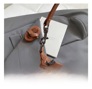 Detail of brown suede handbag featuring dark silver metal hooks and spare shoulder strap