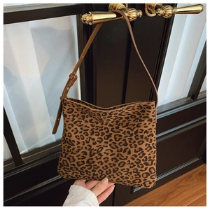 Dettaglio della borsa a spalla leopardata con tracolla in pelle marrone sulla porta