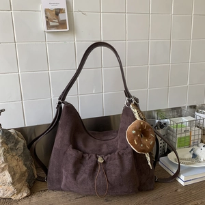 Detalle del bolso tote de ante marrón oscuro con bolsillo de cordón y colgante de dona