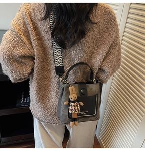 Detail of grey suede handbag with houndstooth strap and a cute rabbit charm accessory