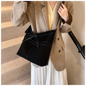 Détail du sac cabas en suédine noire avec surpiqûres blanches et nœud décoratif élégant