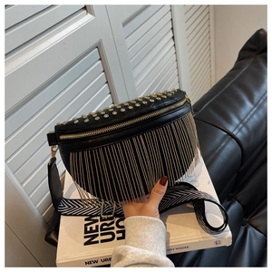 Détail de sac banane en cuir noir avec clous dorés, franges et bandoulière tissée large