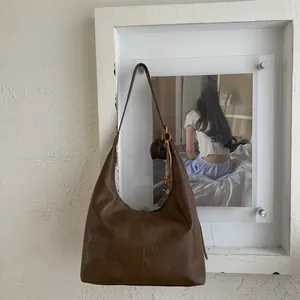 Detail of vintage brown Hobo bag with natural leather texture and heart shaped charm