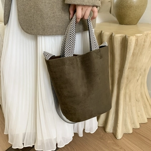 Detail of suede bucket bag with woven herringbone strap and fine stitching craftsmanship