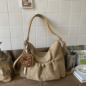 Vista detallada del bolso tote de ante caqui con un colgante de donut de peluche