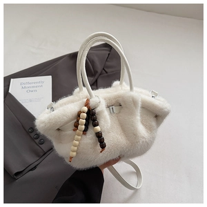 Detailansicht der weißen Plüschhandtasche mit Holzperlenanhängern im Ethno-Stil und weichem Fell