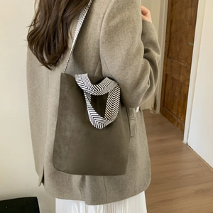 Side view of dark brown suede bucket bag with black and white herringbone wide strap