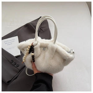 Detail einer weißen Plüschtasche mit Metallschnalle und Holzperlen-Anhänger-Zubehör