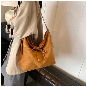 Sac cabas en daim marron avec surpiqûres contrastées et nœud décoratif sur un mannequin