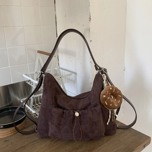 Detalle de bolso hobo de gamuza marrón con bolsillo de cordón y colgante de donut suave