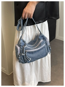 Detail of vintage denim crossbody bag featuring multiple zipper pockets and textured straps