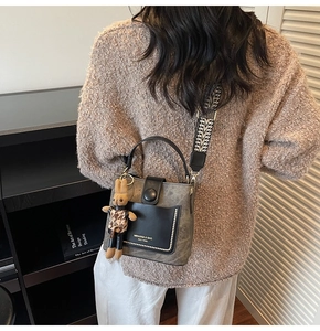 Detail of vintage gray bucket bag featuring wide ripple strap and plush rabbit charm