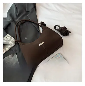 Detail of dark brown matte suede hobo bag with silver buckle and knotted handle