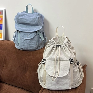 Zaini in nylon con coulisse in blu e beige su un divano dal design moderno