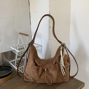Primer plano de bolso hobo de gamuza marrón con cordón y colgante de dona suave