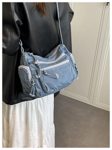 Blue denim crossbody bag featuring multiple zipper pockets shown on model back view