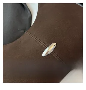 Detail view of brown leather shoulder bag featuring lychee texture and silver oval buckle