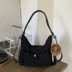Detalle de bolso hobo de ante negro con bolsillo de cordón y colgante de donut