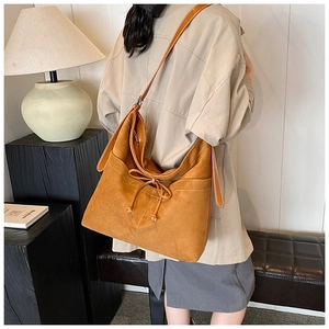 Detail view of suede tote bag with contrast stitching and drawstring decorative accent