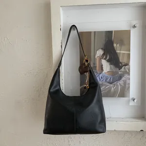 Detail view of black vintage shoulder bag featuring vertical stitching and a heart charm