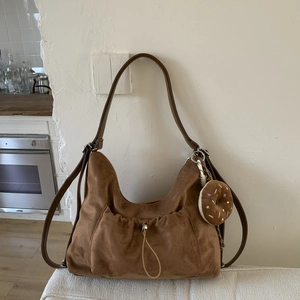Detalle de bolso hobo de ante marrón con bolsillo de cordón y adorno de peluche de donut