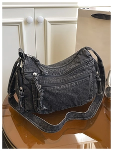 Detail view of dark grey washed denim crossbody bag with multi-zipper pocket design