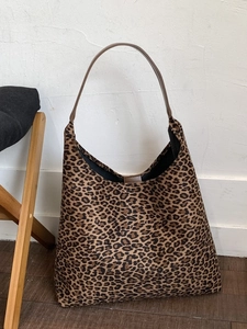 Grote hobo tas met luipaardprint en leren riem op een minimalistische houten vloer