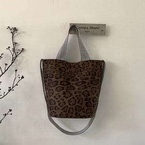 Close-up of leopard print bucket bag with chevron woven shoulder strap hanging on a wall