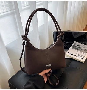 Detail of a dark brown hobo shoulder bag with silver buckle on a leather stool