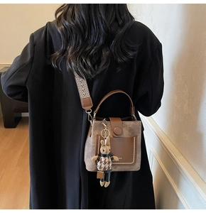 Detail of a brown bucket bag with marble texture and a woven ethnic shoulder strap